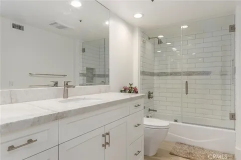 a bathroom with a granite countertop toilet a sink a mirror a bathtub and shower