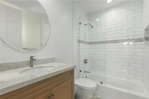 a bathroom with a granite countertop sink a toilet and shower