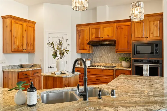 a kitchen with stainless steel appliances granite countertop a sink a stove and a wooden floors