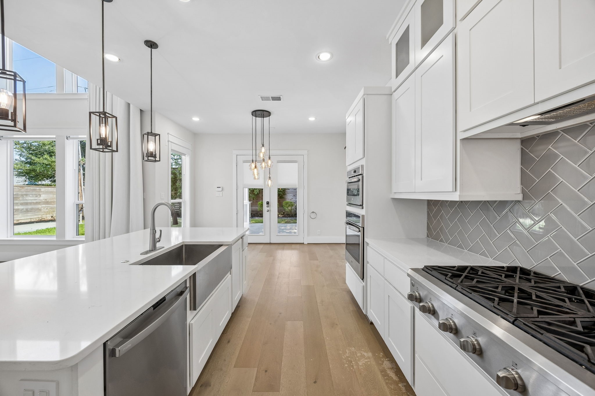 8558 Ridgepoint Drive Houston, TX 77055 - Photo 5 of 39 White cabinetry, a herringbone backsplash, and an expansive island create a bright setting for everyday gathering. Virtually staged; island finish digitally altered.