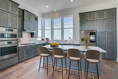a kitchen with a dining table chairs cabinets and stainless steel appliances