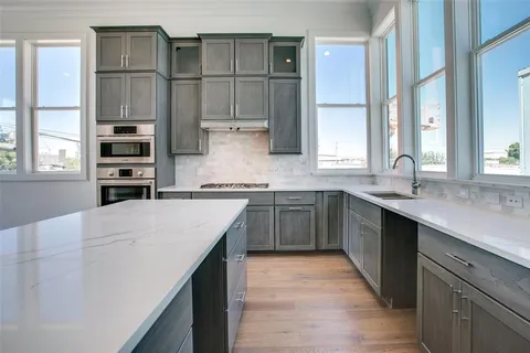 a kitchen with kitchen island granite countertop a sink cabinets and stainless steel appliances