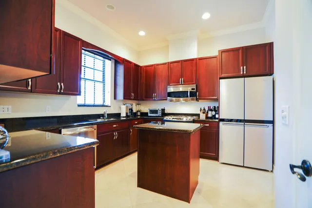 a kitchen with stainless steel appliances granite countertop a refrigerator a sink dishwasher a stove top oven a large refrigerator and cabinets with wooden floor