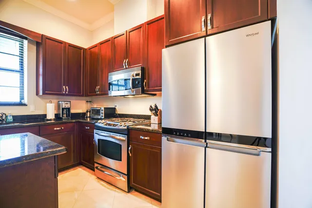 a kitchen with stainless steel appliances granite countertop a refrigerator a sink and a stove