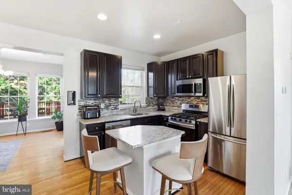 a kitchen with stainless steel appliances a refrigerator a stove a dining table and chairs