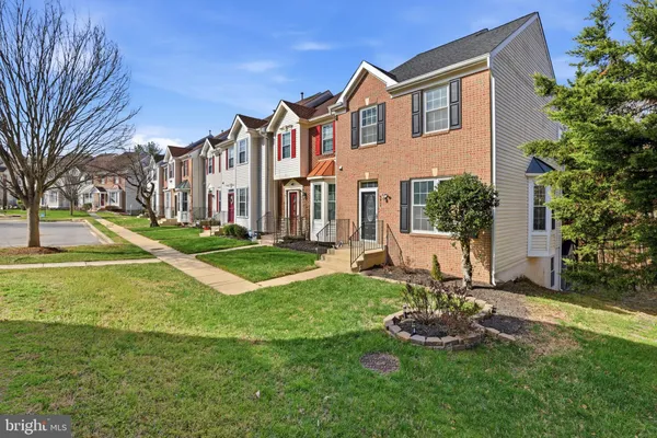 a view of a house with a big yard and potted plants and large trees