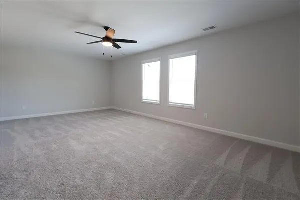 an empty room with chandelier fan and windows