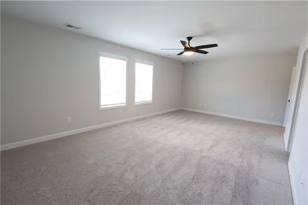 an empty room with windows and ceiling fan