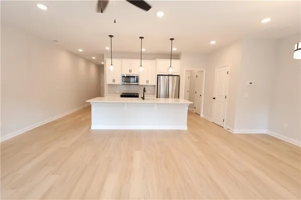 a view of kitchen with stainless steel appliances refrigerator oven and white cabinets