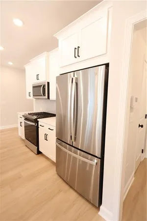 a kitchen with stainless steel appliances a refrigerator a stove a sink and white cabinets