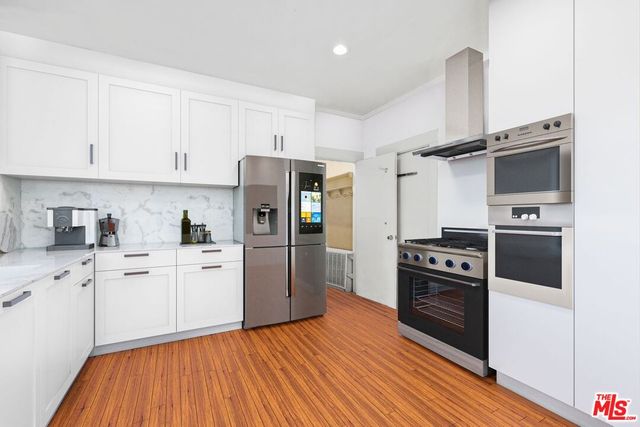 a kitchen with stainless steel appliances a refrigerator stove and wooden cabinets