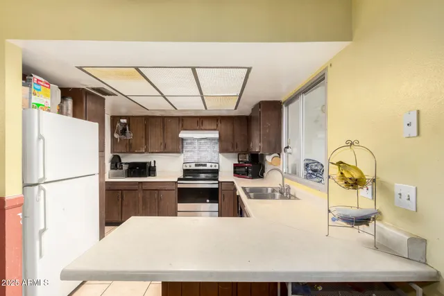 a kitchen with stainless steel appliances a stove a sink a refrigerator white cabinets and wooden cabinets