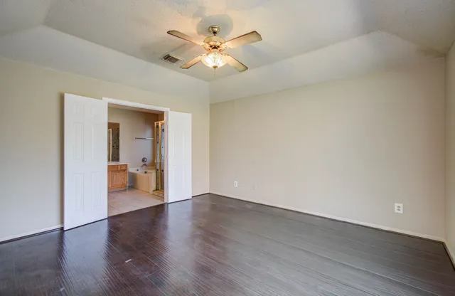 an empty room with wooden floor and a ceiling fan