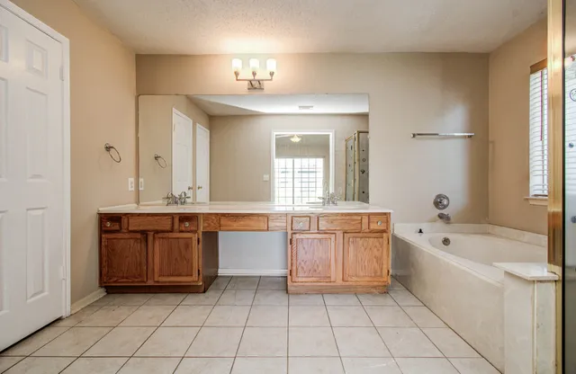 a large bathroom with a granite countertop tub a double vanity sink a window and a mirror