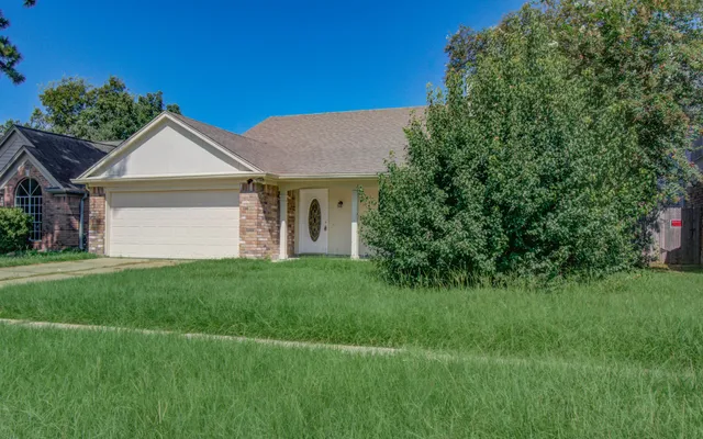 a view of a house with a big yard potted plants and a large tree