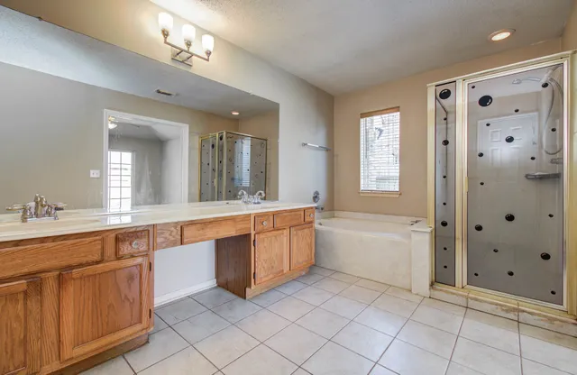 a large white bathroom with a double vanity sink a large mirror and a bathtub