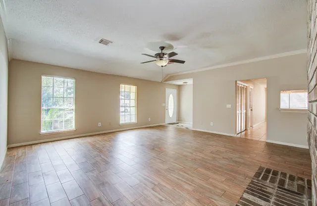 a view of an empty room with window and wooden floor