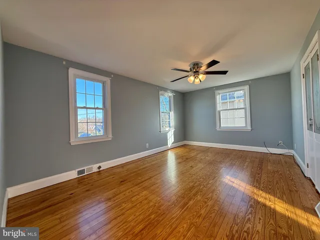 a view of empty room with wooden floor and fan