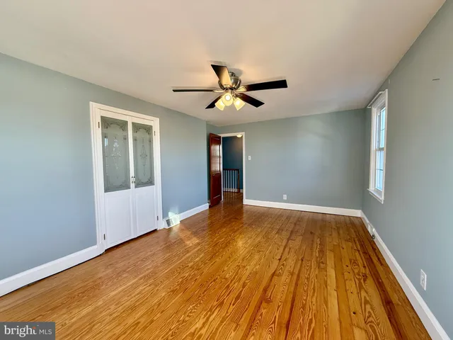 an empty room with wooden floor and windows