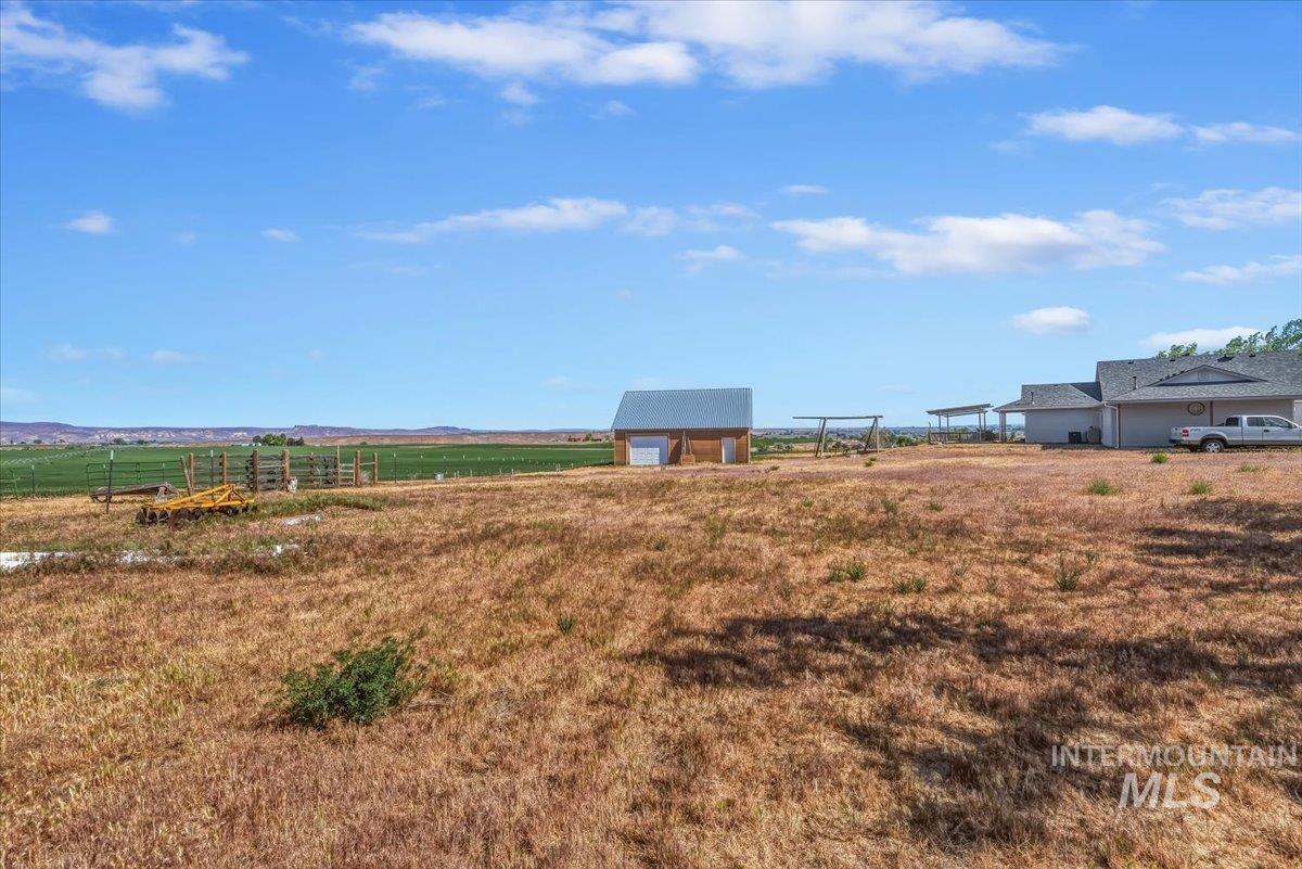 2331 Gulley Road Homedale, ID 83628 - Photo 44 of 46 Expansive open land featuring a detached shed with a metal roof, a single-story residence with a covered patio, and distant green fields