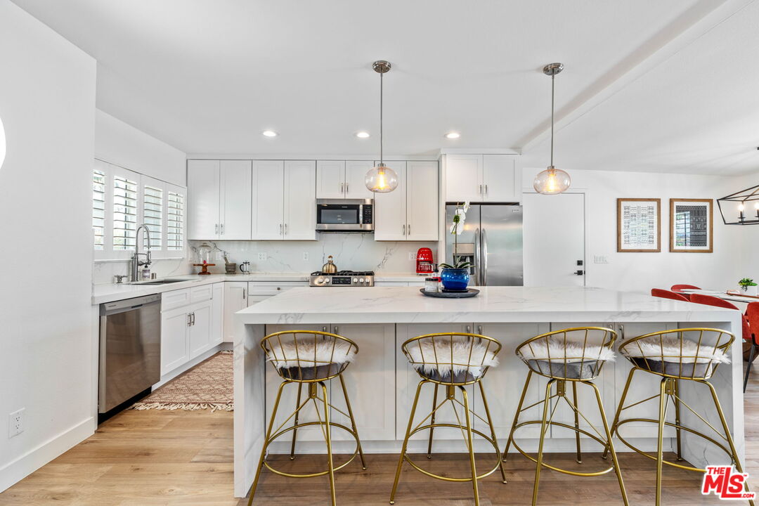 1399 Tamarisk Road Palm Springs, CA 92262 - Photo 12 of 28 a kitchen with stainless steel appliances granite countertop white cabinets and wooden floor