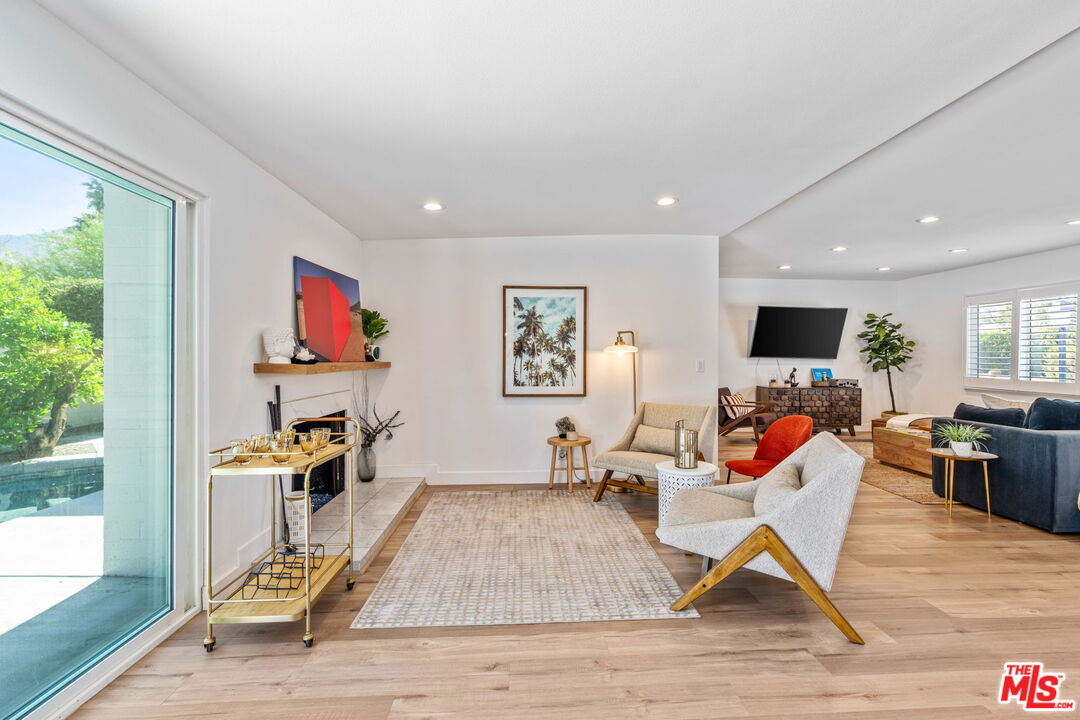 1399 Tamarisk Road Palm Springs, CA 92262 - Photo 6 of 28 a living room with furniture a flat screen tv and a floor to ceiling window