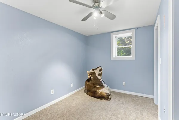 an empty room with windows and fan