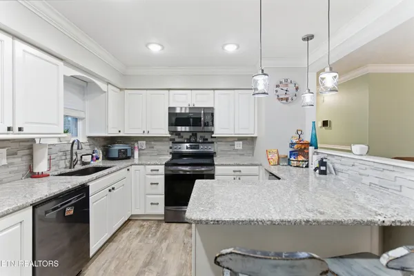 a kitchen with kitchen island granite countertop a sink cabinets and stainless steel appliances