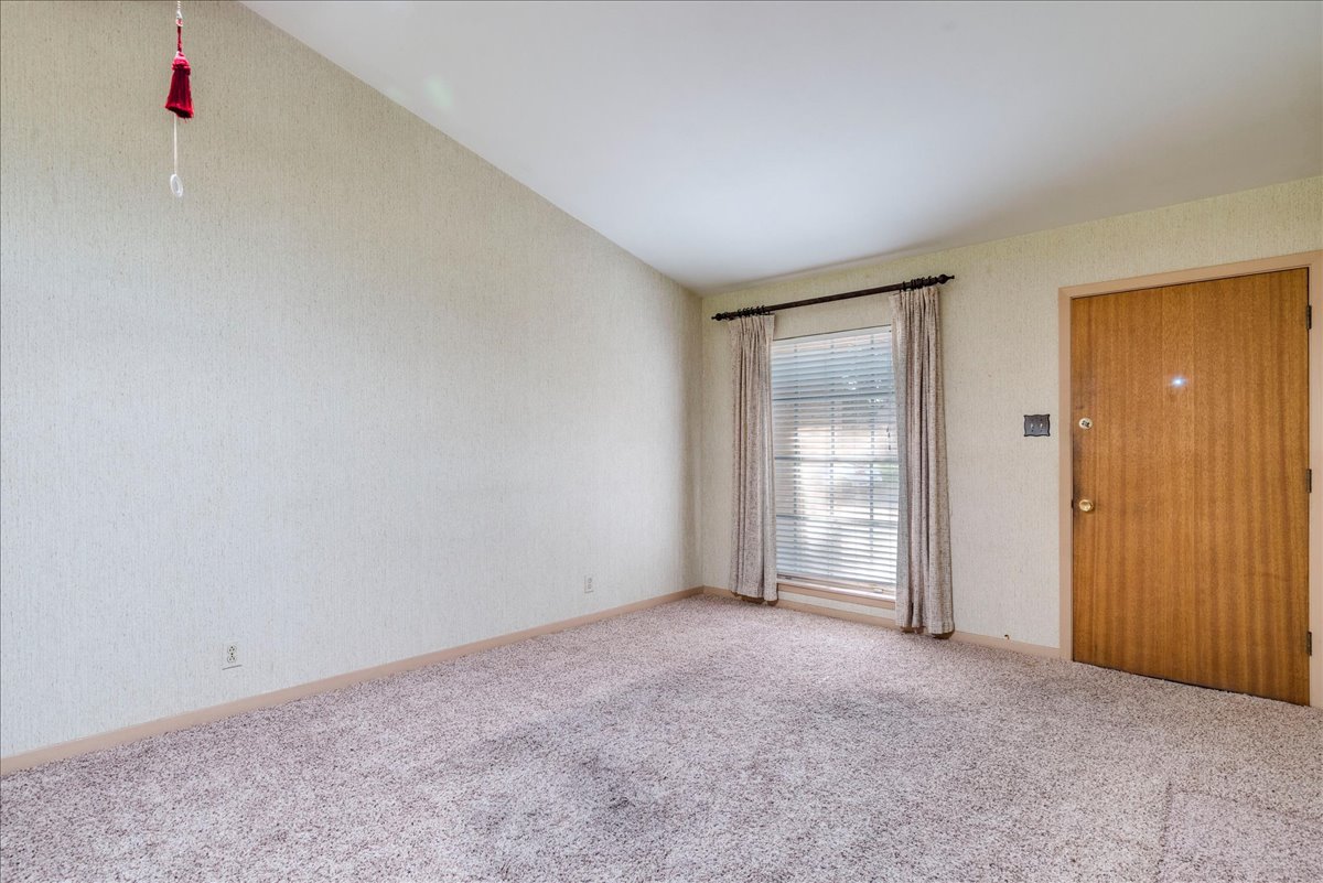 6626 Isabelle Drive Austin, TX 78752 - Photo 9 of 27 Living room featuring textured walls, neutral-toned carpeting, a window with horizontal blinds and drapery, and a wood-panel entry door