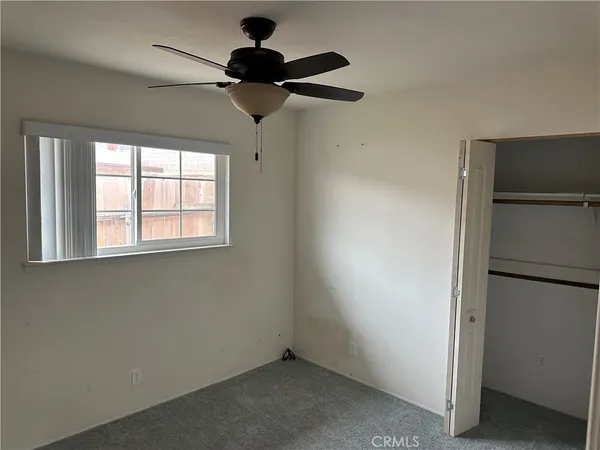 an empty room with a window and a ceiling fan