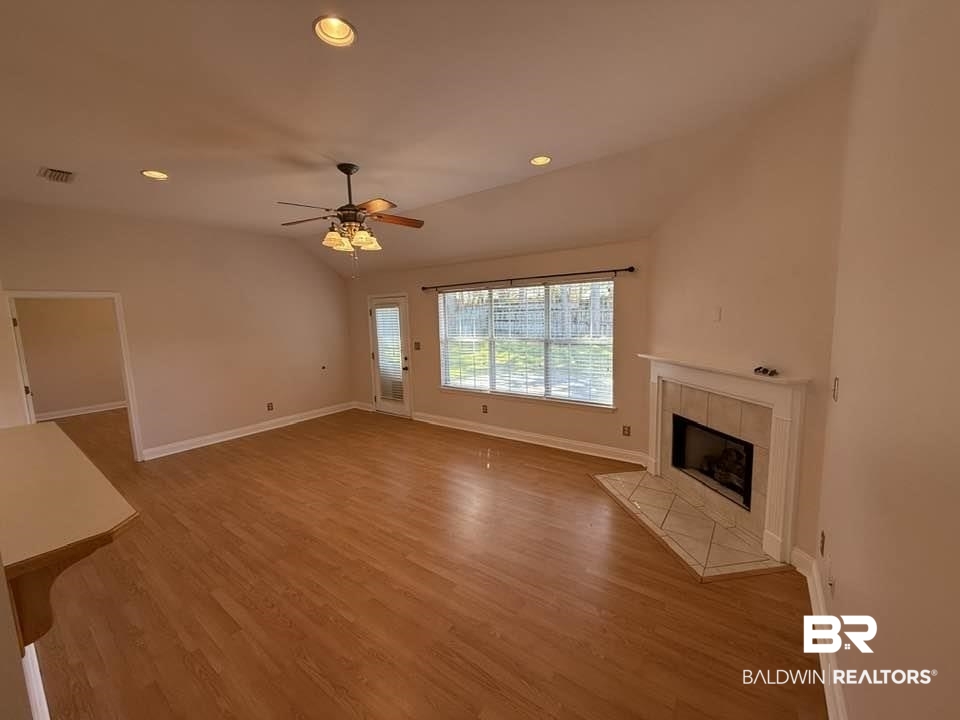 10428 South Side Loop Fairhope, AL 36532 - Photo 9 of 28 Unfurnished living room with lofted ceiling, a fireplace, wood finished floors, and visible vents