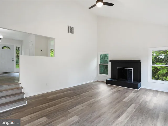 a view of an empty room with wooden floor fireplace and a window