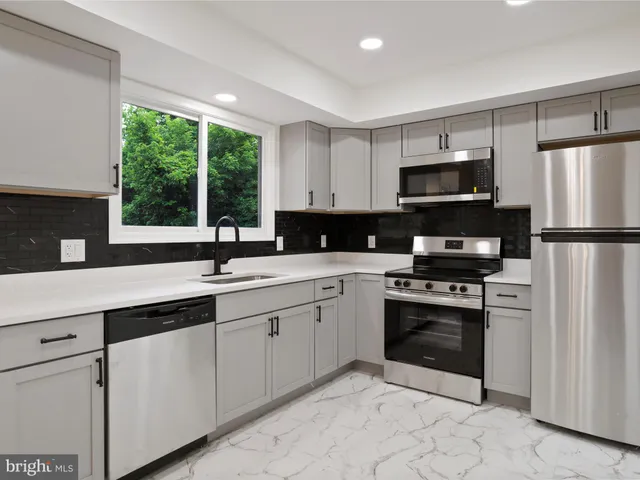 a kitchen with appliances a sink cabinets and a window