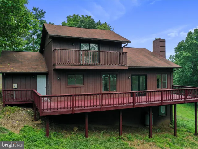 a view of a house with a wooden deck and furniture