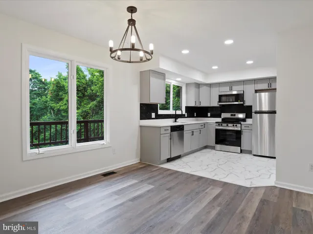 a kitchen with stainless steel appliances granite countertop a stove top oven a sink and a wooden floor