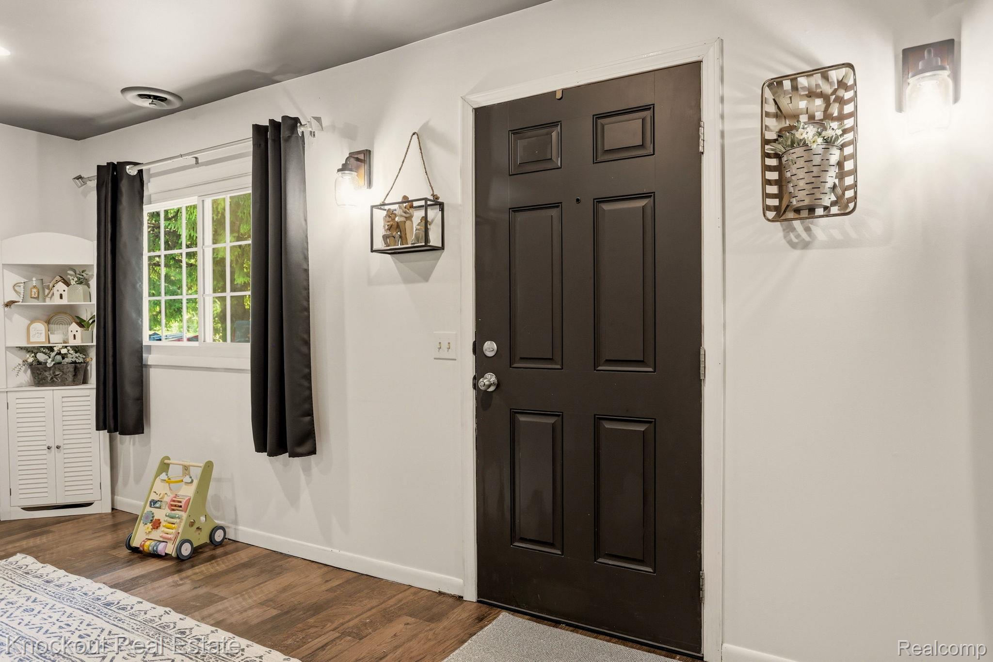 8845 Ormes Road Vassar, MI 48768 - Photo 5 of 35 Paneled entry door with dark finish, wall-mounted sconces, and wood-finish flooring