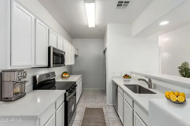 a kitchen that has a lot of cabinets a sink and wooden floor