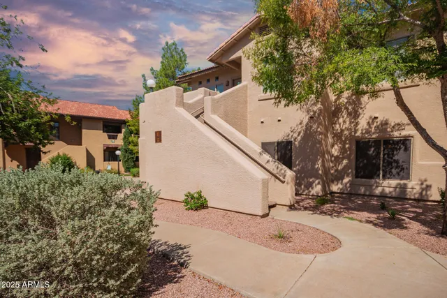 a view of a white house with a tree and plants