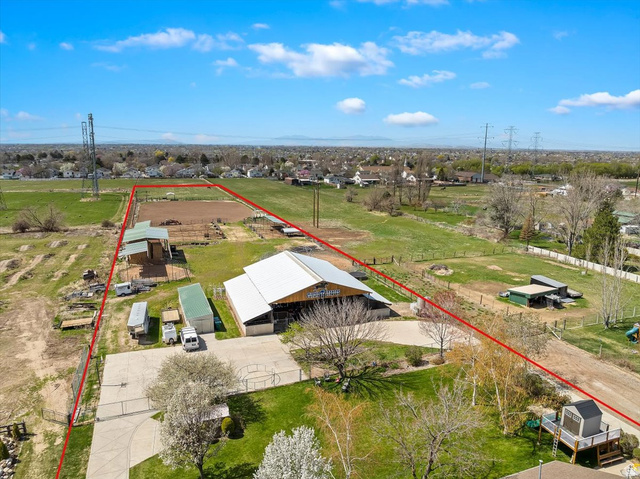 5321 South 3100th Street West Roy, UT 84067 - Photo 61 of 64 Expansive property featuring a large barn structure with a light-colored roof, a dirt riding arena, and multiple outbuildings