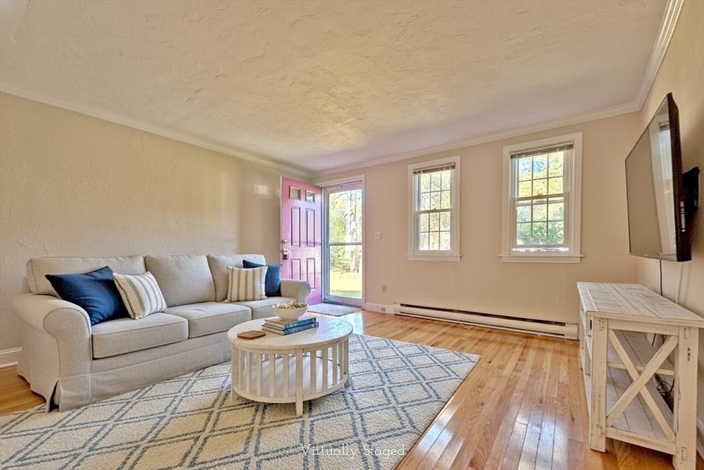 a living room with furniture and a dining table with wooden floor