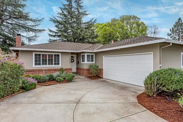 a view of a house with brick walls and a yard with plants