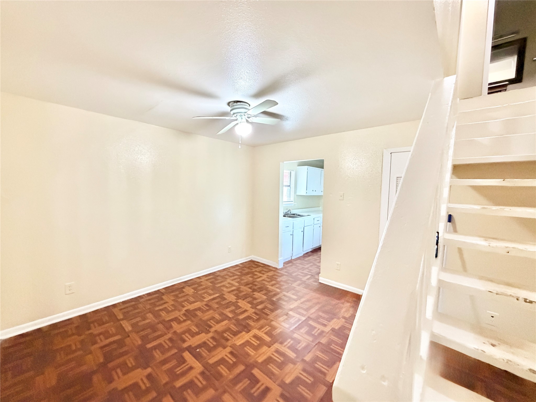 6257 Manor Road, Unit B Austin, TX 78723 - Photo 5 of 38 Living area featuring wood-finish parquet flooring, a ceiling fan with integrated lighting, and a white baseboard trim