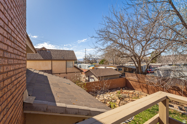 892 Cambridge Drive St. George, UT 84770 - Photo 55 of 65 Upper-level exterior showing a brick facade, multi-level roofing, and a wooden balcony railing