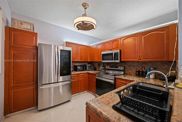 a kitchen with stainless steel appliances granite countertop a refrigerator stove top oven a sink and dishwasher