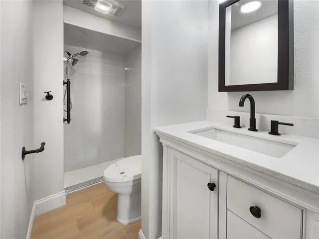 a bathroom with a granite countertop sink a toilet and a mirror