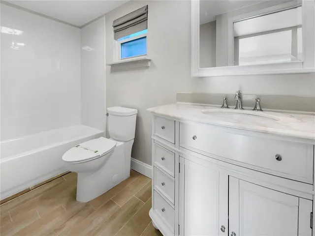 a bathroom with a granite countertop toilet sink and mirror
