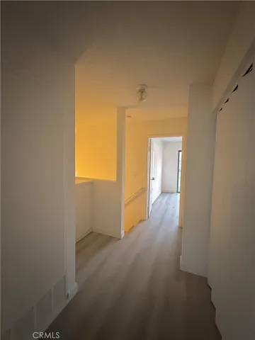 a view of a hallway with wooden floor and a bathroom