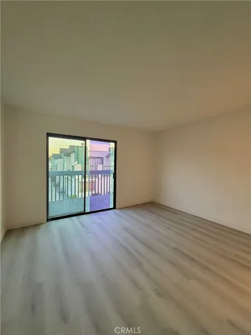 a view of an empty room with wooden floor and windows