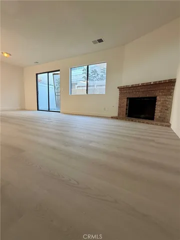 a view of an empty room with a fireplace and a window