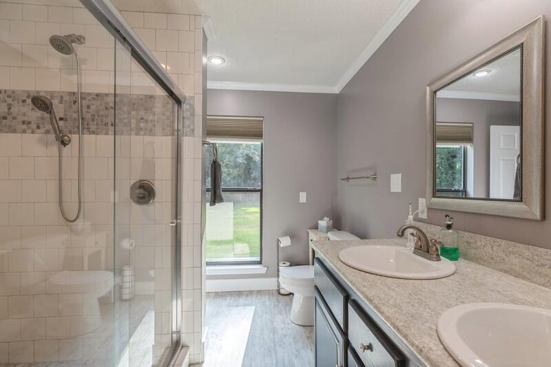 5540 Old River Road Baker, FL 32531 - Photo 16 of 37 a bathroom with a granite countertop sink a mirror and a shower